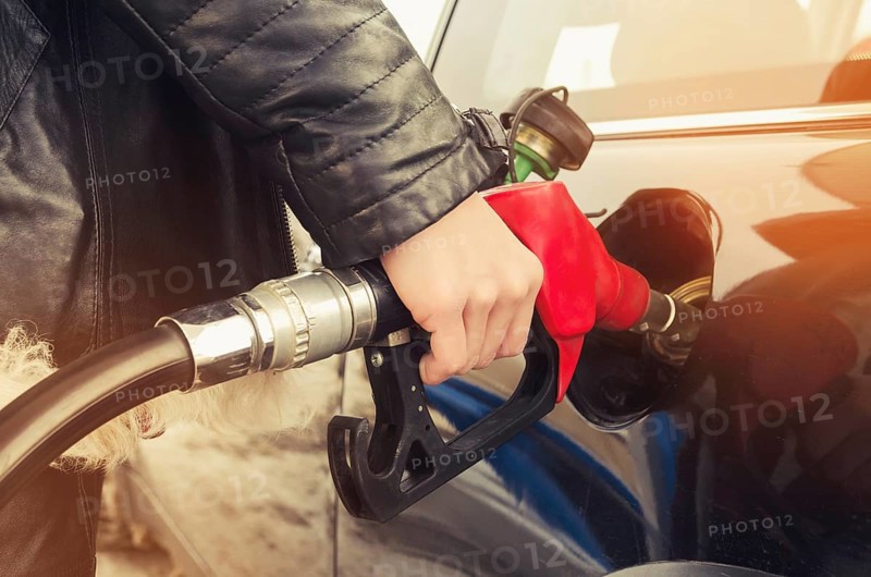 Hipster woman in sunglasses fills gasoline car