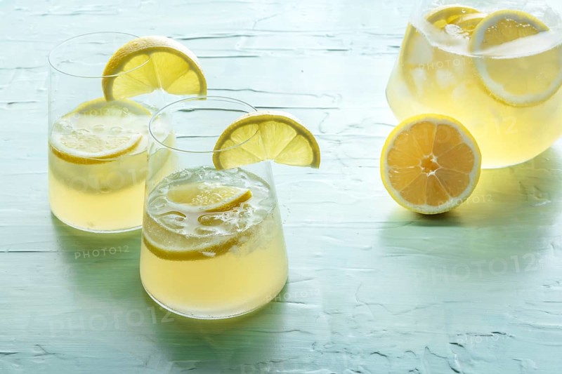 Lemonade. Lemon water drink with ice. Two glasses and a pitcher on a blue background. Detox beverage. Fresh homemade cocktail, Food photography, Food photography