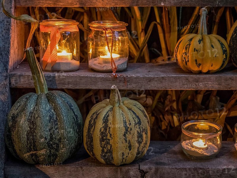 Various pumpkins and candles in jars on a wooden shelf as a cosy Halloween decoration at night, borken, münsterland, Germany, Europe