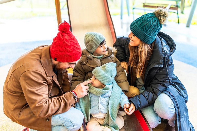 Parents and children enjoying quality time together on a slide at the playground, embracing the joy of winter with laughter and smiles