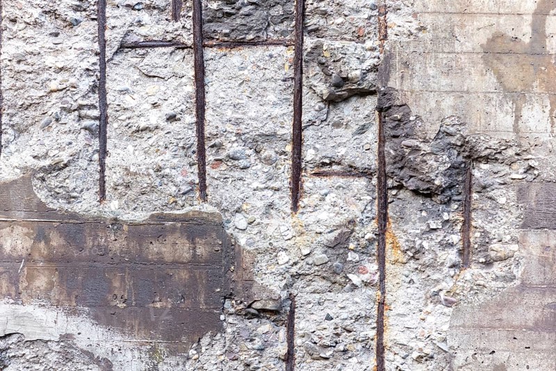 Textured concrete wall with exposed rebar and a rustic look
