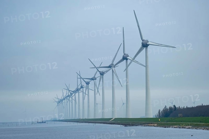 Wind turbines in a row on the coast in the mist and fog