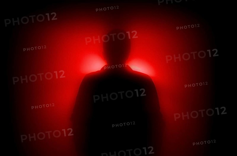 A diffuse figure in the red backlight, concept image, fear, anonymity, AI generated