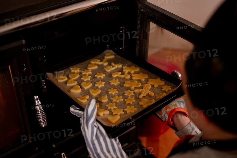 Baking tray with Christmas biscuits is placed in the oven