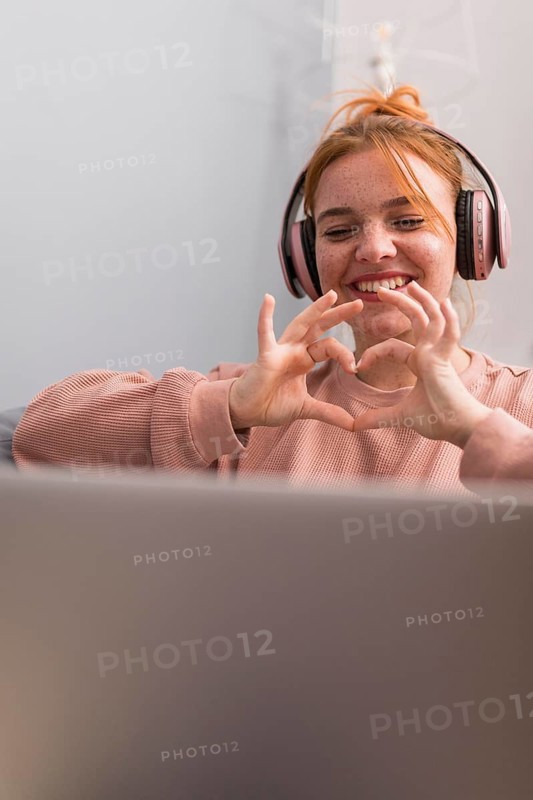 Smiley female teacher showing heart sign students during online class