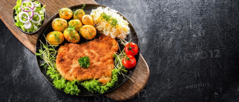 Pork breaded cutlet coated with breadcrumbs served with potatoes and cabbage