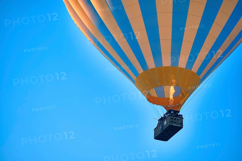Flying hot air balloon against bright blue sky