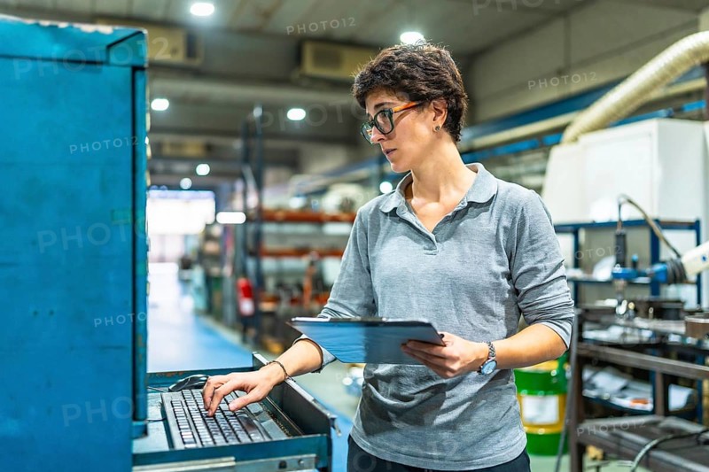 Female adult manager of a factory using computer while checking the quality of products and doing inventory