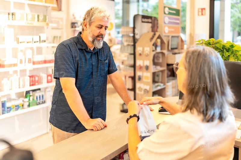 A mature man standing on the counter of a store shopping medicines on pharmacy
