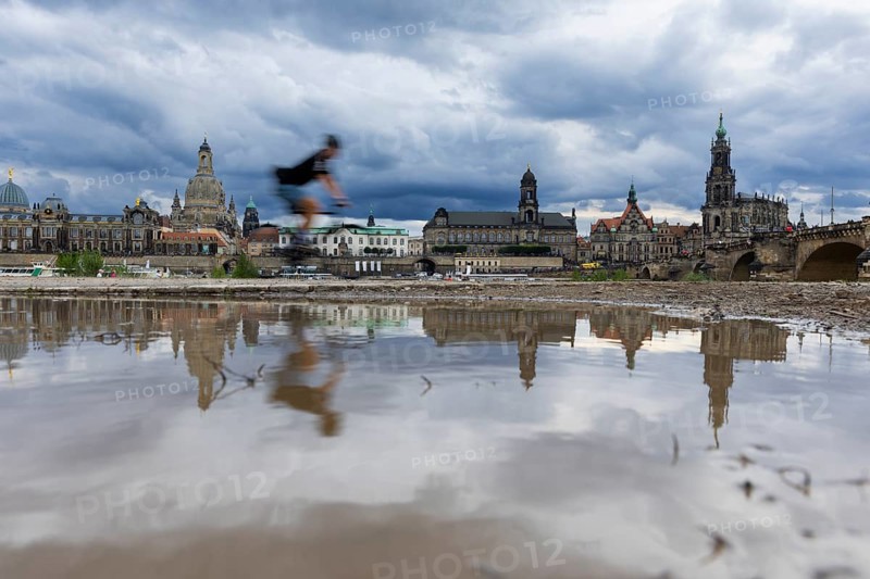 The Dresden silhouette with a cyclist and dark clouds behind the Church of Our Lady is reflected in a puddle on the Elbe cycle path, Elbe cycle path, Dresden, Saxony, Germany, Europe