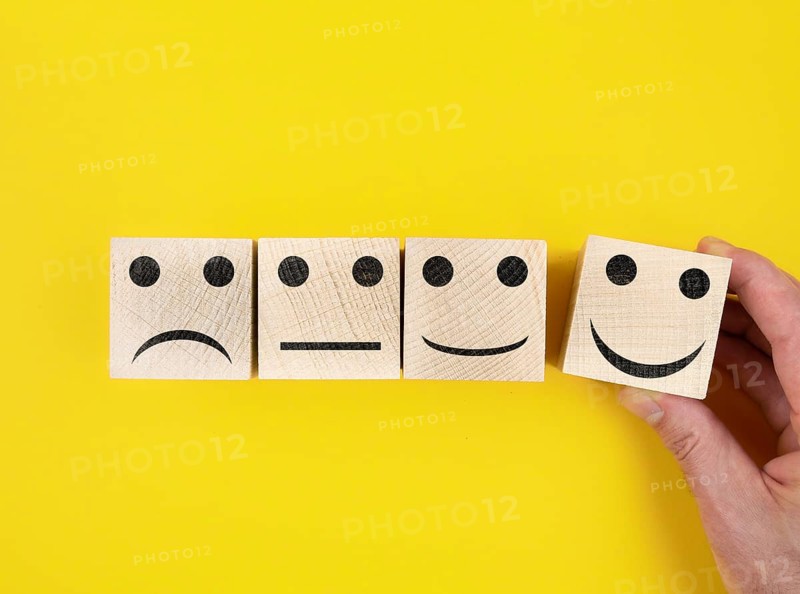 directly above view of smiley feedback icons on wooden blocks against yellow background