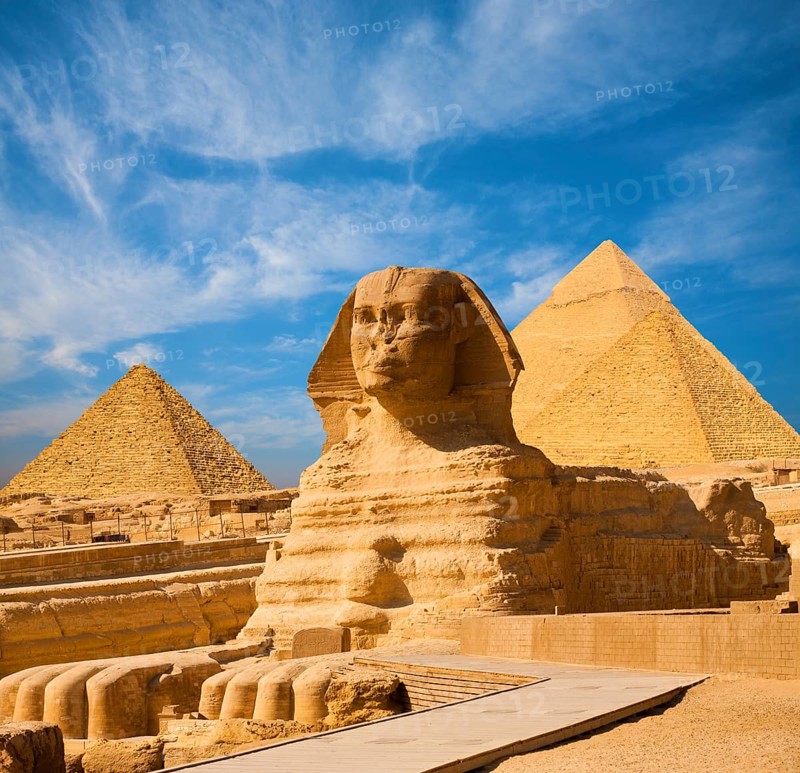 Egyptian Great Sphinx full body portrait with head, feet with all pyramids of Menkaure, Khafre, Khufu in background on a clear, blue sky day in Giza, Egypt empty with nobody. copy space