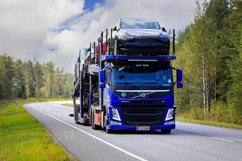 Blue Volvo FM car carrier Autolink Oy hauls Tesla and other new cars on road 25 from Hanko Port to mainland. Raasepori, Finland. September 9, 2021