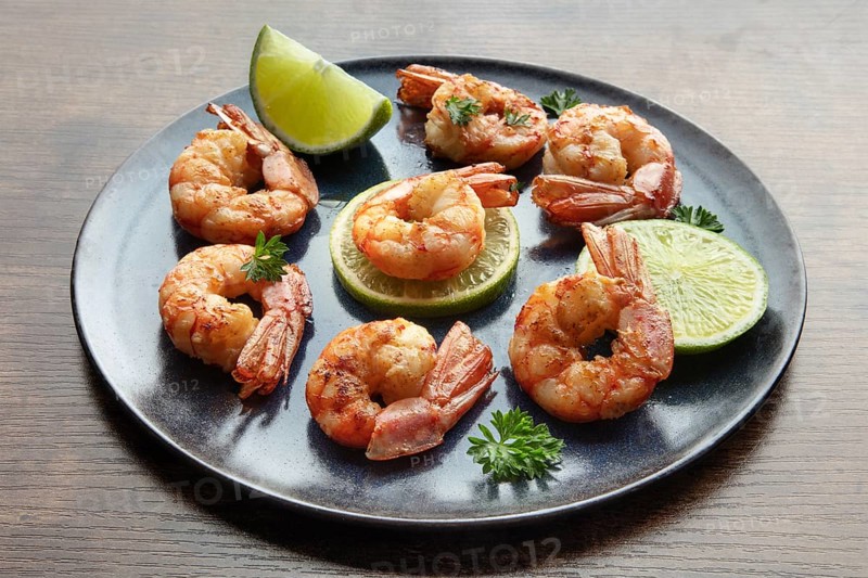 Shrimps with limes and parsley. Grilled shrimp on a rustic table. Spicy seafood appetizer