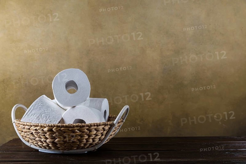 Rolls of toilet paper in the basket on the wooden background