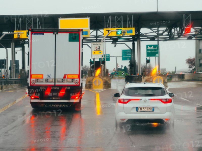 Car waiting at a toll booth with traffic lights and payment lanes on a rainy day, A1 A8 highway near Milan, Italy, Europe