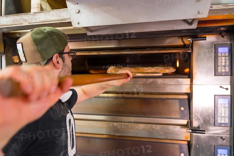 Baker of bakery in the workshop artisan workshop baking loaves in the oven