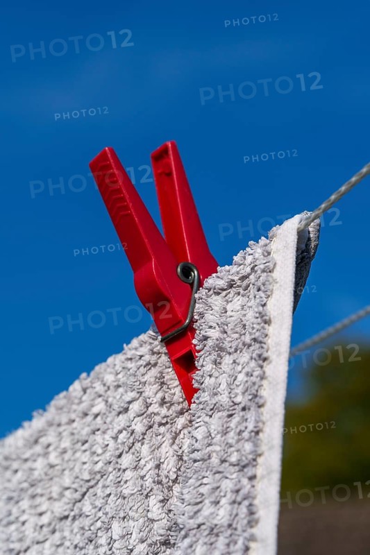 Red clothes peg holding a wet towel on a clothesline, in front of a blue sky, Weseke, Münsterland, Germany, Europe