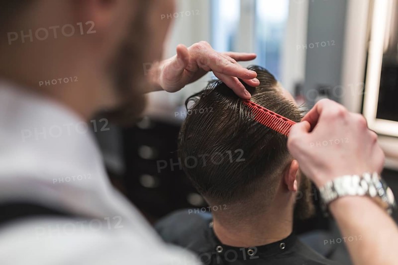 Faceless barber combing hair man before cutting