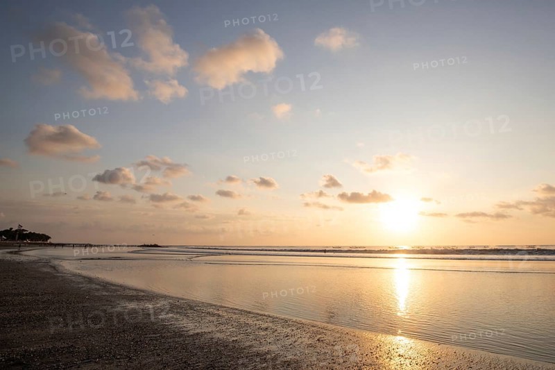 Dreamlike sunset on the dream beach of Kuta, small waves sunset over the sea and the reflection of the sky in the shallow water. Topical Bali in Indonesia