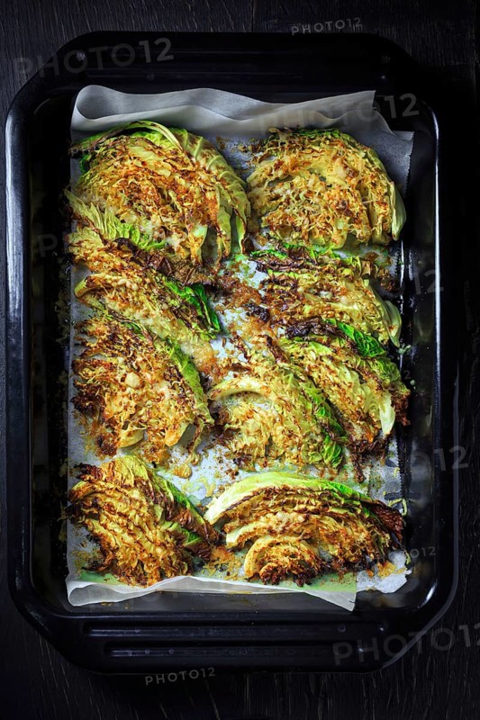 Baked savoy cabbage with parmesan cheese, honey and spices on baking sheet