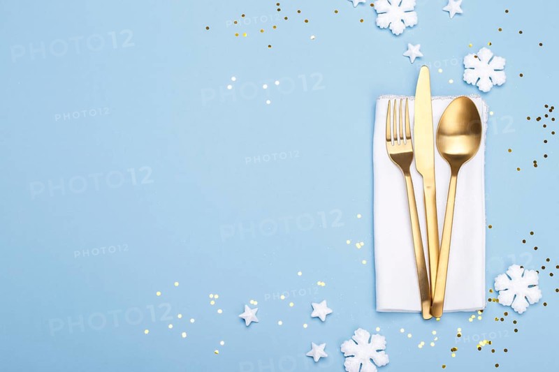 Christmas or new year table setting with golden cutlery on the blue background with copy space