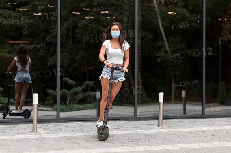 Woman with mask riding electric scooter