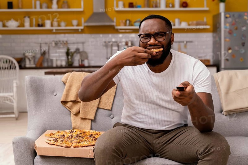 Man watching tv eating pizza