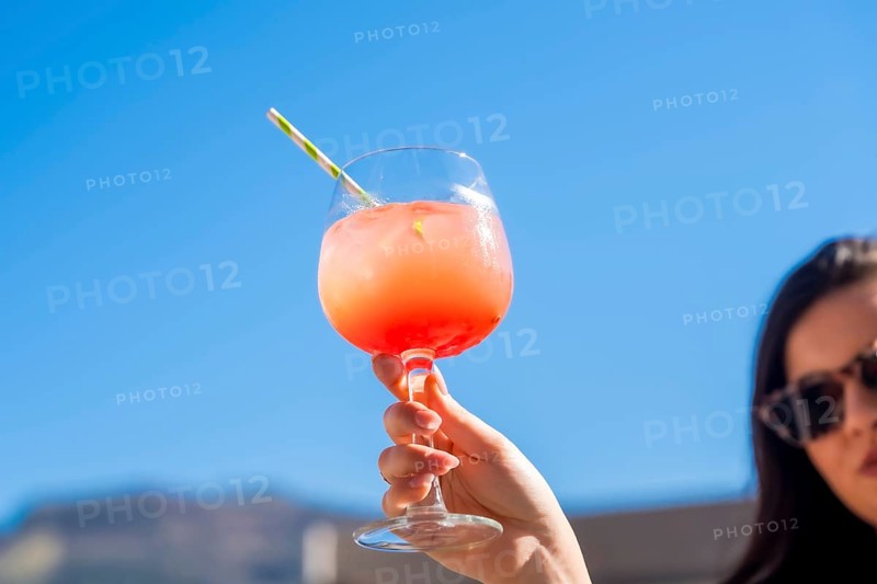Woman raising a cocktail glass with sex on the beach cocktail in a rooftop