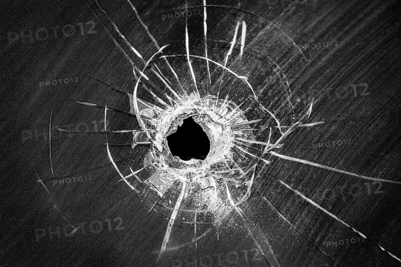 Bullet shot cracked hole on car windshield or accident damaged broken house window glass
