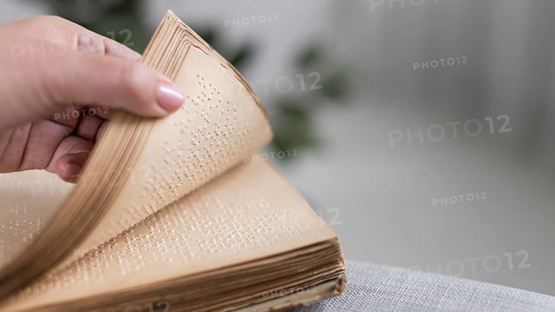 Close up hand holding old braille book