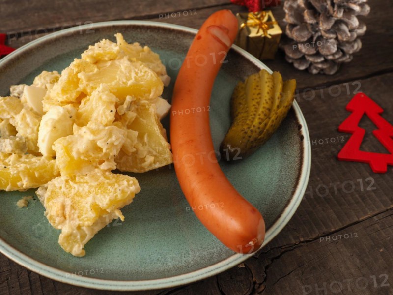 Tasty homemade potato salad with organic sausage and gherkin, traditional Christmas meal