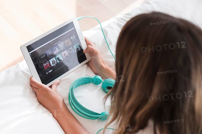 Young woman holding tablet with spotify app. High resolution photo