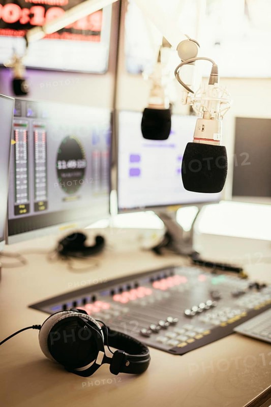 Studio microphone in a broadcasting radio studio, mixer and computer in the blurry background