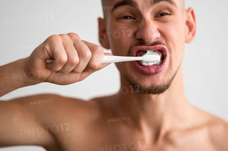 Front view man brushing his teeth morning