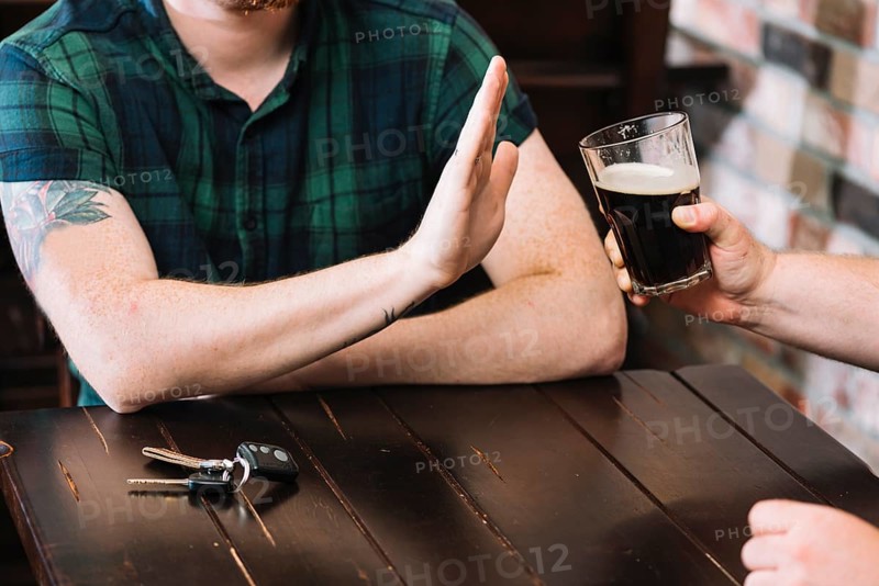 Man refusing glass rum offered by his friend