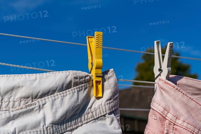 Yellow and white clothes pegs holding pink clothes on a clothesline under a blue sky, Weseke, Münsterland, Germany, Europe