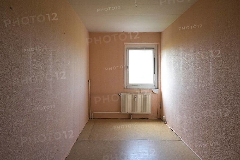 Cramped unrenovated room intended as enough space in a typical rental apartment in social housing with cheap flooring, exposed pipes and poorly insulated window, copy space, selected focus