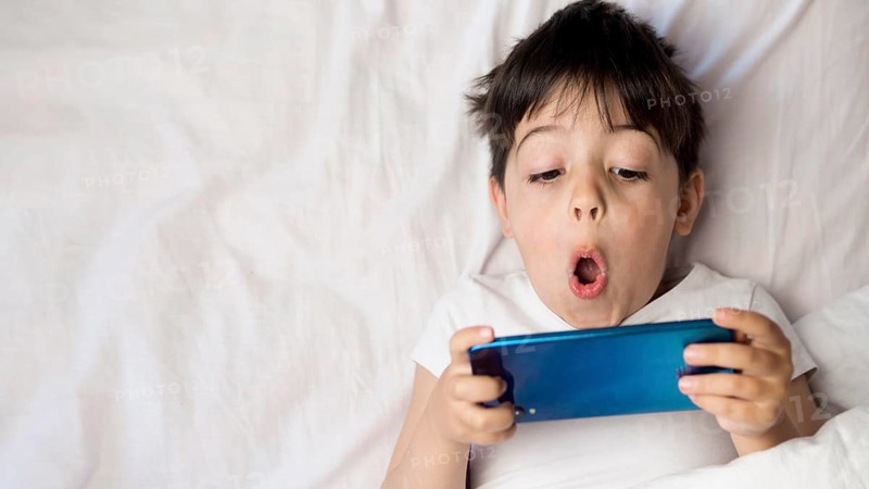 Flat lay kid with phone bed