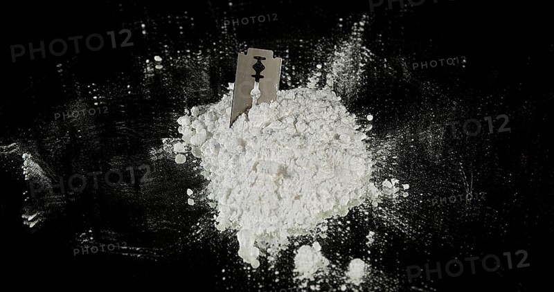 Powder Drug Falling on Razor Blade and Syringes against Black Background