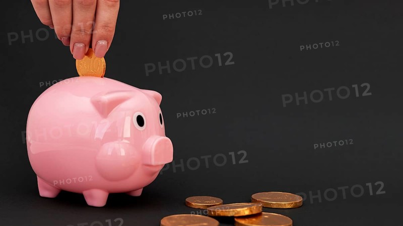 Person putting pink piggy bank coins