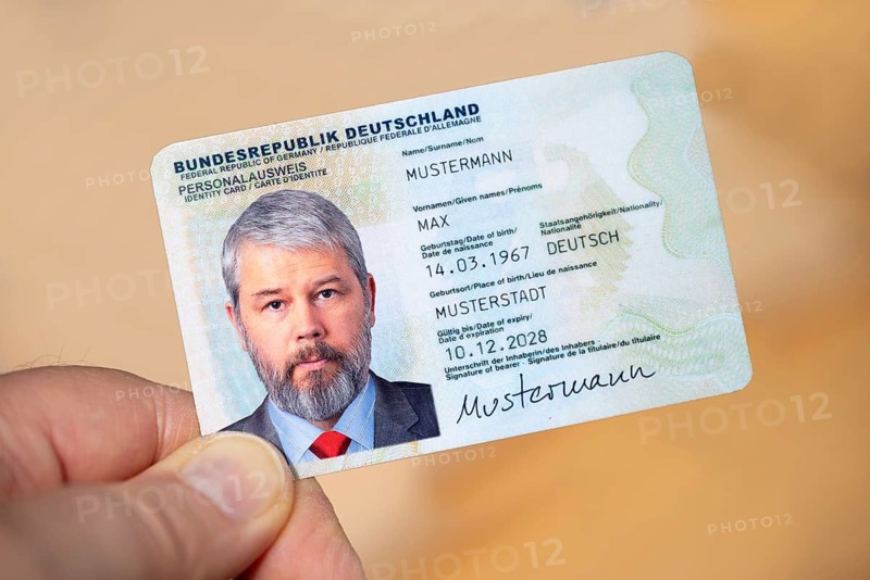 Hand holding an identity card of the Federal Republic of Germany with a businessman around 50 years old