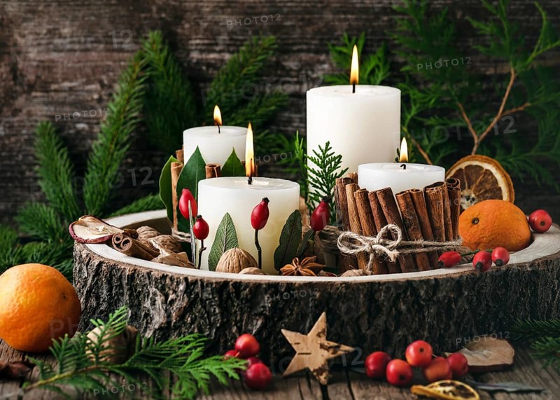 Advent wreath with four white burning candles decorated with natural materials. Slices of freshly dried apple, orange and spices. Rustic style. Handmade decoration for Christmas