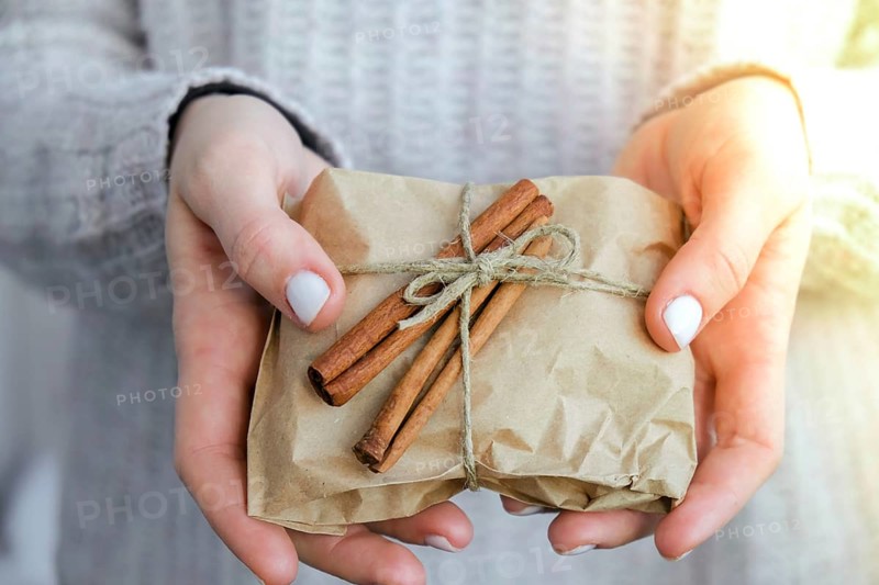 Woman giving Box with New Year's gifts, wrapped in craft paper and decorated with cinnamon sticks. Holidays and Gifts concept. Handmade Eco friendly alternative green Christmas presents zero waste Sustainable lifestyle