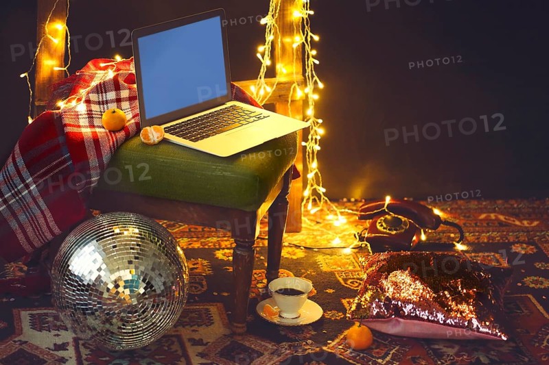 New Year's eve or Christmas still life with retro phone, disco ball, notebook, coffee, candle and blanket, golden background