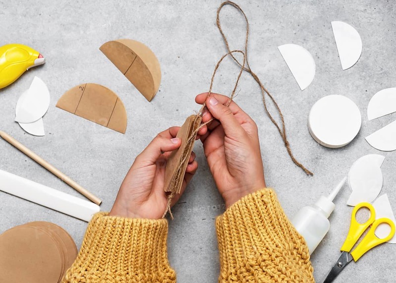 Step 6 Add a string to the inner edge of the ball. Making festive Christmas tree decorations from coffee filter paper. Handicraft, crafting with children. Step by step instructions