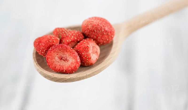 Strawberries (dried) as high detailed close-up shot on a vintage wooden table, selective focus