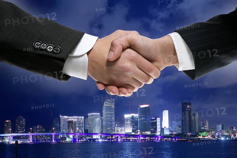 Businessman handshake in Miamy downtown night cityscape