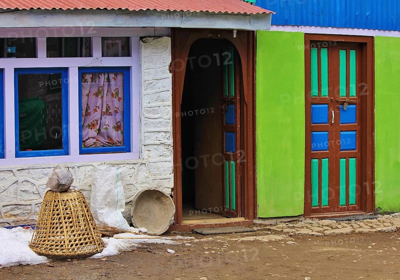 Colorful painted doors and facade. Braided basked used for transporting goods. Scene in Nepal