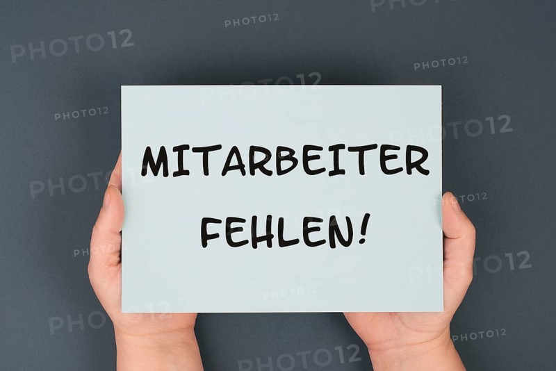 The words shortage of employees are standing in german language on the paper, skilled workers are missing